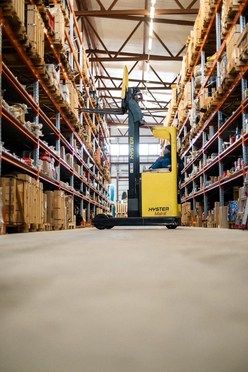 Photo by Kseniia Ilinykh Forklift driver operating a reach truck in a warehouse aisle, representing forklift driver recruitment