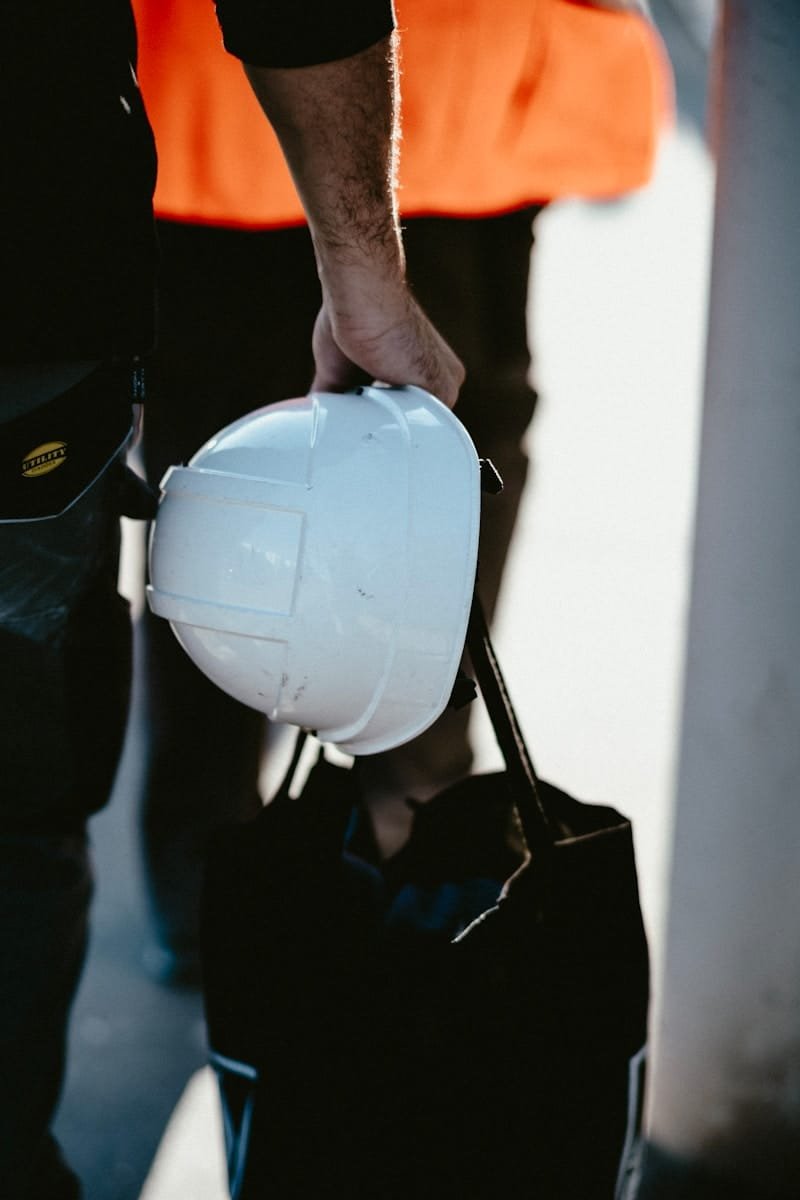 Photo by Mathias Reding Site manager holding a white hard hat on a construction site, representing site manager recruitment
