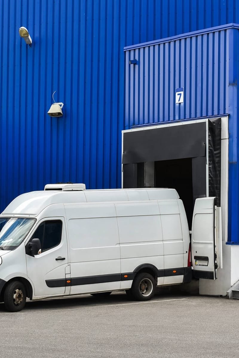 van driver recruitmetn agency White panel van parked at a blue warehouse loading bay with the rear doors open