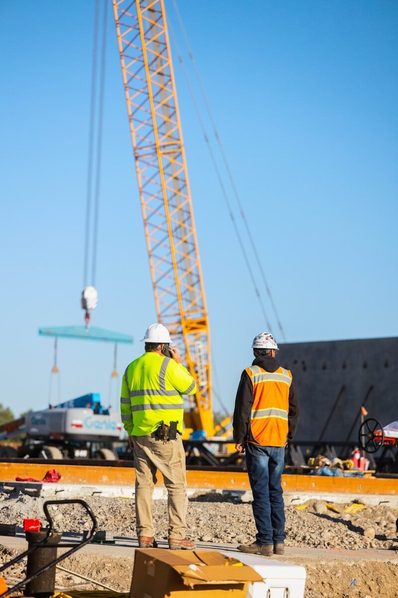Labourer recruitment Construction workers observe a crane lifting materials.