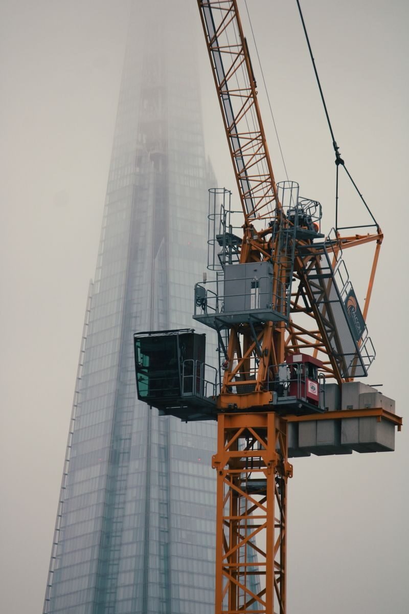 Photo by Sarthak Maji Tower crane rising through fog beside The Shard in London, the kind of lifting site our crane operators are recruited for.